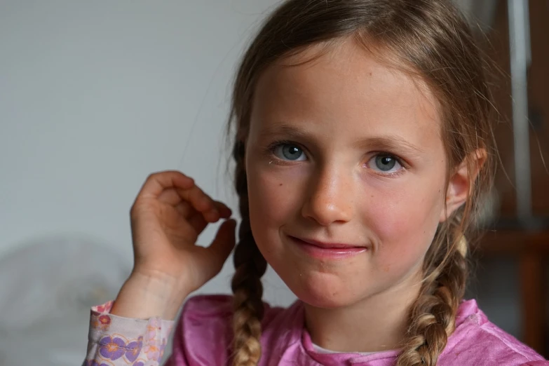 a close up of a child with braids on her hair, inspired by Sophie Anderson, candid portrait photo, 7 0 mm portrait, portrait of nordic girl, hand on cheek