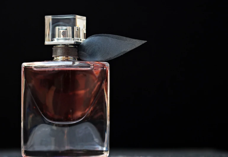 a bottle of perfume sitting on top of a table, by Niko Henrichon, pixabay, with a black background, crimson peek, pictured from the shoulders up, stock photo