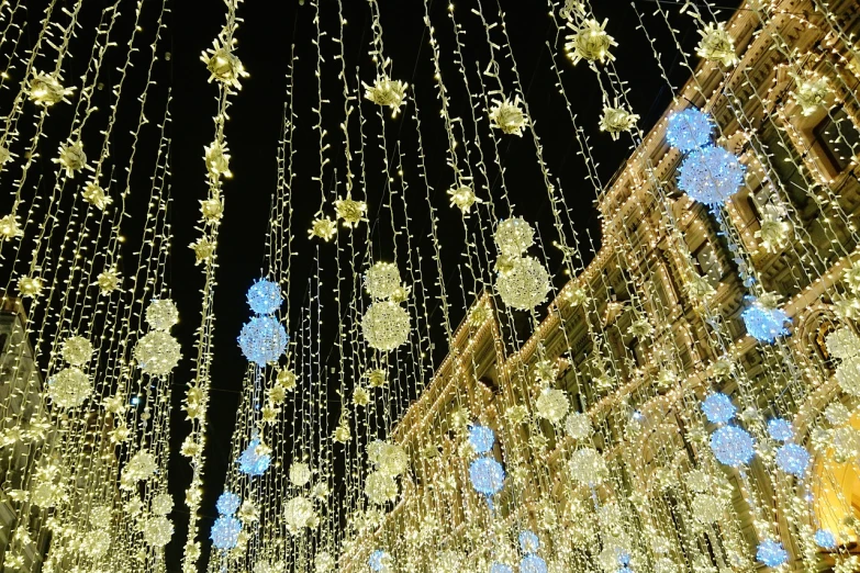 a street filled with lots of lights covered in snowflakes, a photo, baroque, clematis like stars in the sky, low angle photo, in moscow centre, blue and yellow ribbons