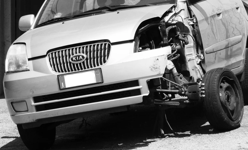 a black and white photo of a wrecked car, pexels, long front end, a human, pillar, panel