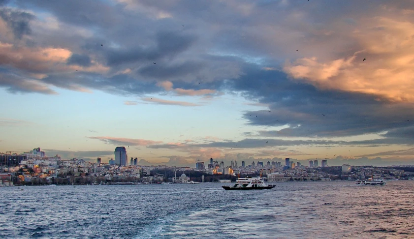 a boat on a body of water with a city in the background, by Cafer Bater, flickr, hurufiyya, istanbul, dramatic sky, busy cityscape, three views