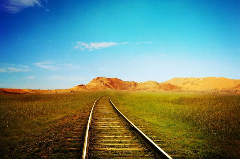 a train track in a field with mountains in the background, by Andrei Kolkoutine, flickr, minimalism, cinematic silk road lanscape, steppe background, clear sky, beautiful wallpaper