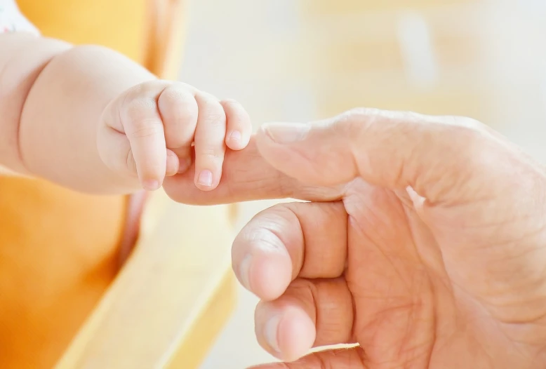 a close up of a person holding a baby's hand, with index finger, next gen, older male, a harmonious integration