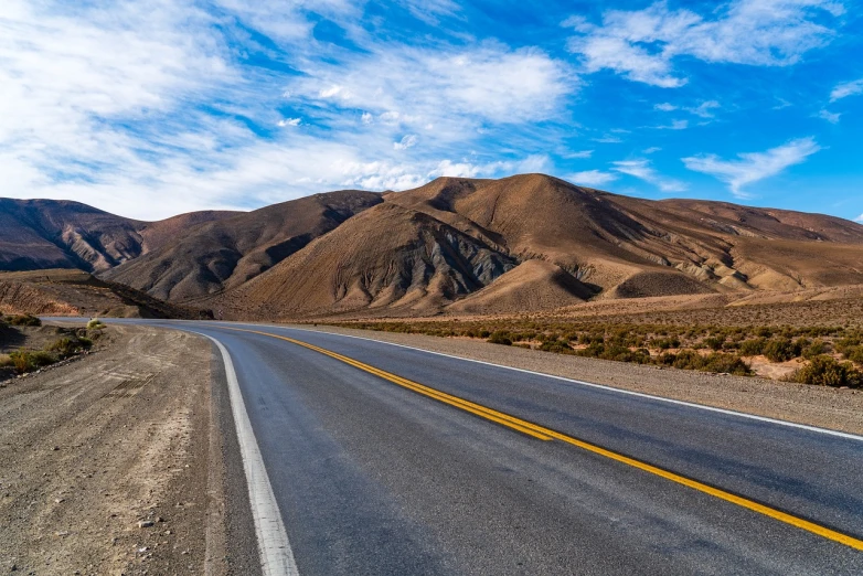 a road in the middle of a desert with mountains in the background, shutterstock, central california, ultra wide angle view, downhill landscape, andes