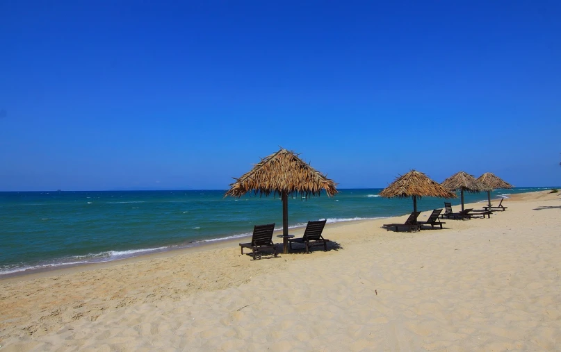 a group of lounge chairs sitting on top of a sandy beach, minimalism, vietnam, thatched roof, summer clear blue sky, full res