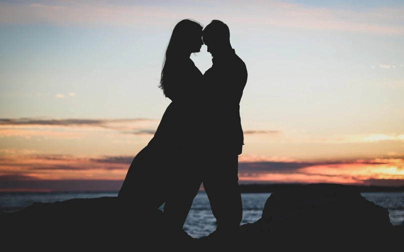 a couple kissing on the beach at sunset, on a cliff, profile image, casey cooke, black