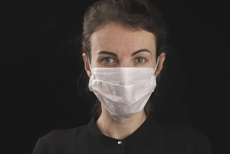 a close up of a person wearing a face mask, a portrait, by Emma Andijewska, shutterstock, antipodeans, female in office dress, on black background, close - up studio photo, medic