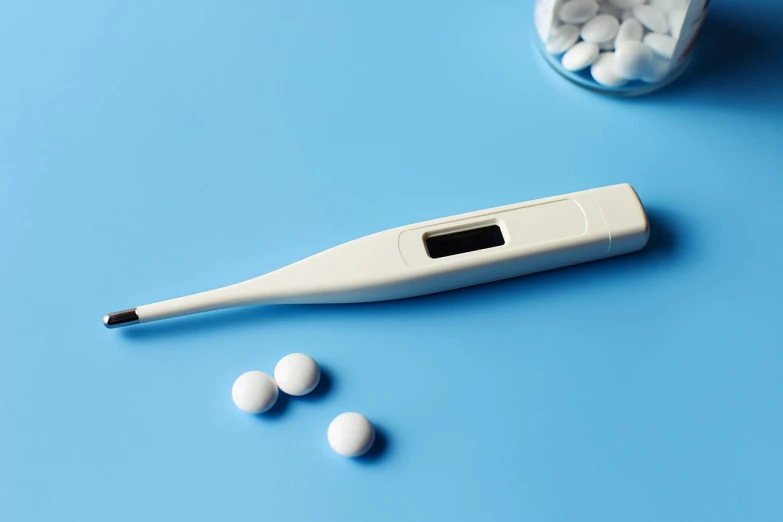 a thermometer and pills on a blue surface, happening, full device, with a long white, top, subtle detailing