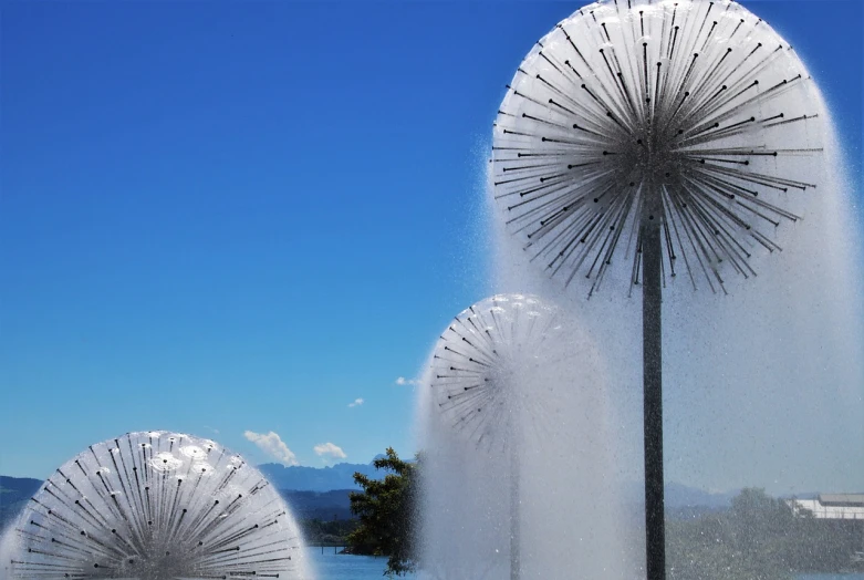 a couple of water spewing out of a fountain, an abstract sculpture, by Cherryl Fountain, environmental art, dandelion, lake kawaguchi, parasols, city views