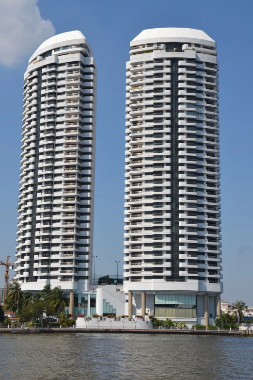 a couple of tall buildings next to a body of water, bauhaus, bangalore, circular towers, ten flats, side-view