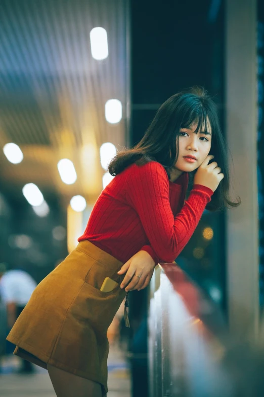 a woman leaning against a wall talking on a cell phone, a picture, by Tan Ting-pho, pexels contest winner, realism, wearing red and yellow clothes, warm glow from the lights, portrait of a cute girl, at a mall