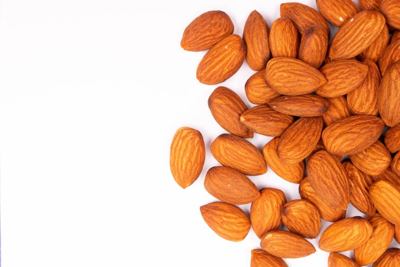 a pile of almonds on a white surface, a stock photo, close-up product photo, view from bottom to top, bottom shot, cover shot