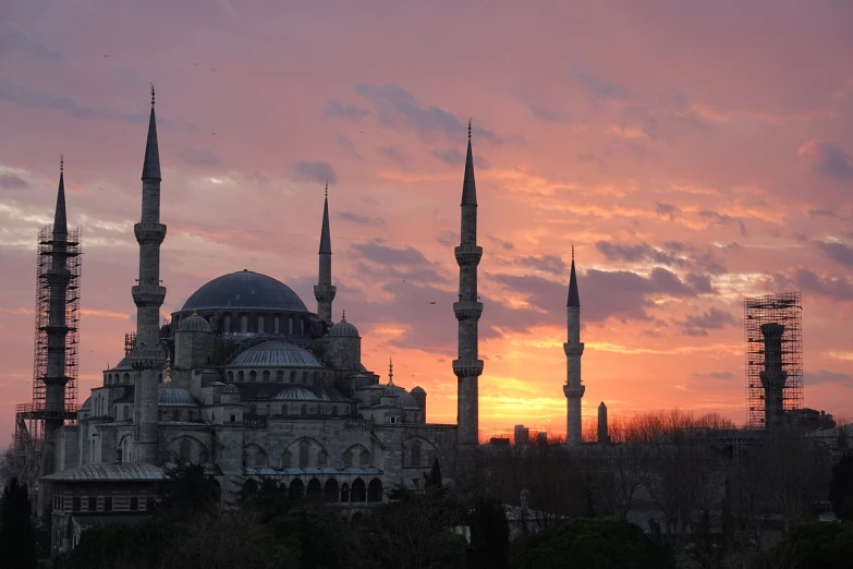 a large building with many spires in front of a sunset, a picture, hurufiyya, turkish and russian, tim, gray, romantic