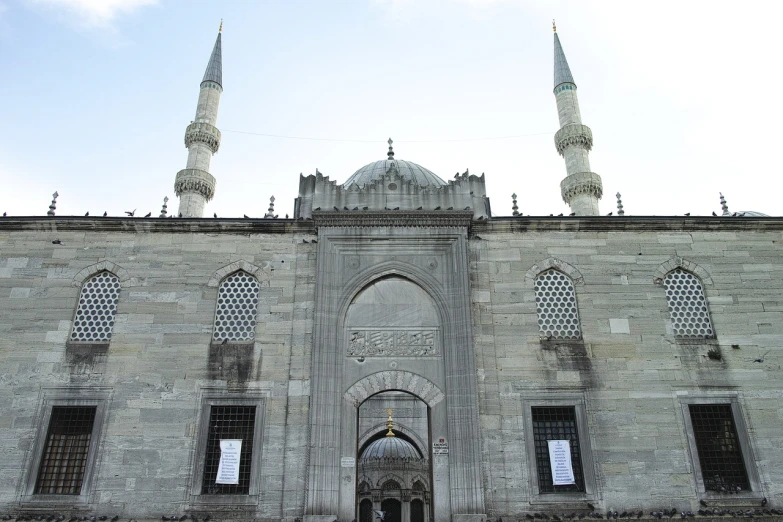 a group of people standing in front of a building, inspired by Fikret Muallâ Saygı, flickr, hurufiyya, mosque interior, stone facade, blue gray, front and side view