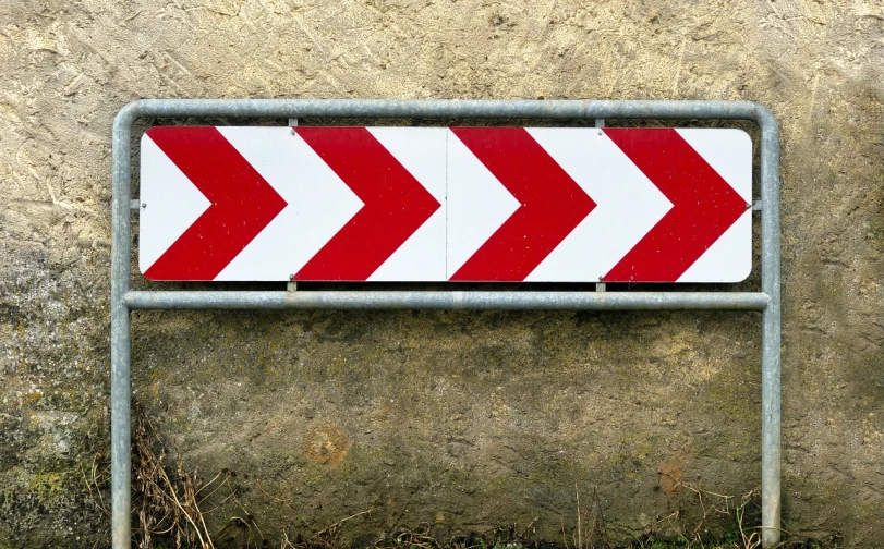 a red and white sign sitting on top of a cement wall, by Francesco Raibolini, pexels, zig zag, thick squares and large arrows, white stripes all over its body, stock photo