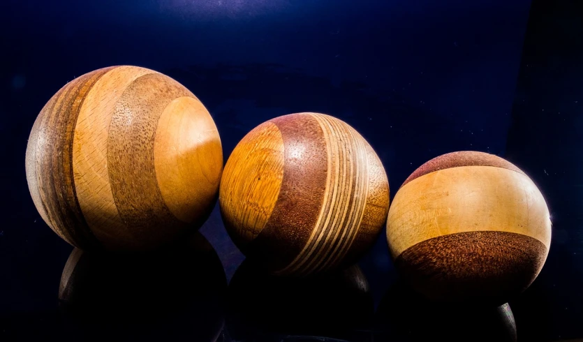 three wooden balls sitting on top of a table, art photography, striations, congas, universe, product photography