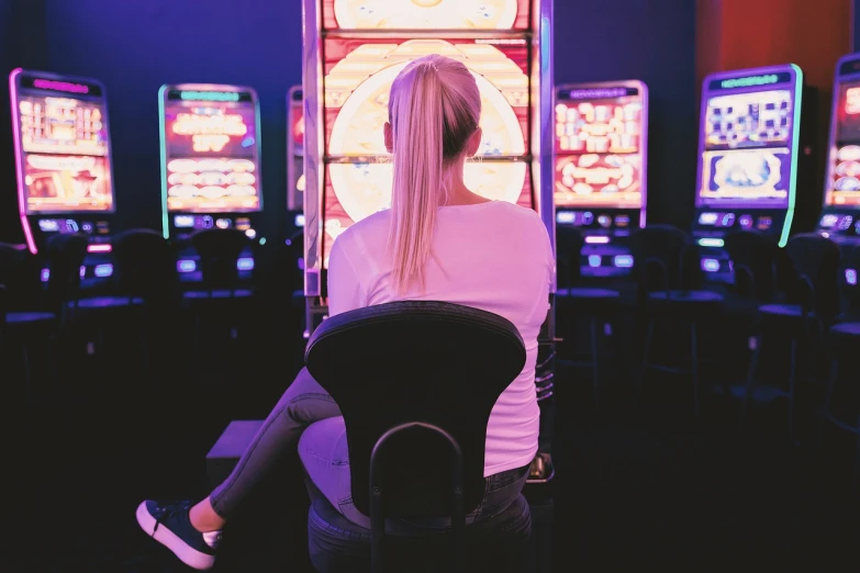 a woman sitting in front of a row of slot machines, a stock photo, by Adam Marczyński, shutterstock, altermodern, shot from the back, blonde woman, cinematic full body shot, in las vegas