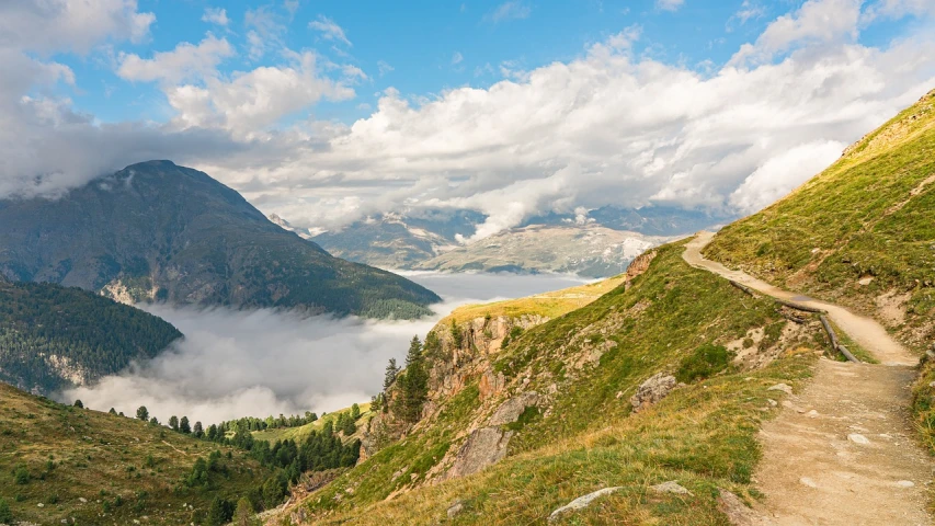 a trail going up the side of a mountain, a picture, by Cedric Peyravernay, shutterstock, above low layered clouds, lakeside, clouds and fields in background, road between hills