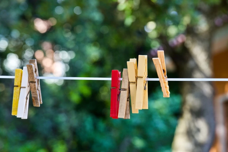 clothes pegs hanging on a clothes line with trees in the background, minimalism, outdoor photo