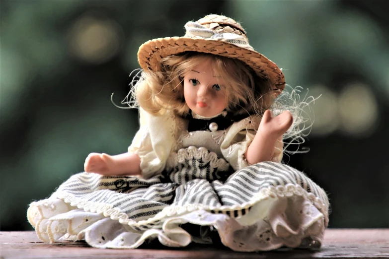 a doll sitting on top of a wooden table, inspired by Kate Greenaway, pixabay, small hat, miniature porcelain model, gypsy, innocent face