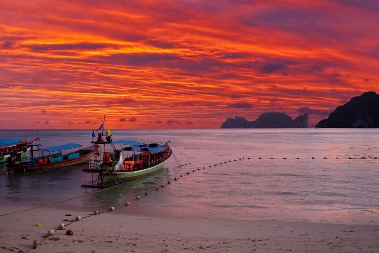a couple of boats sitting on top of a beach, shutterstock, burning clouds, thai, in rich color, f / 3 2