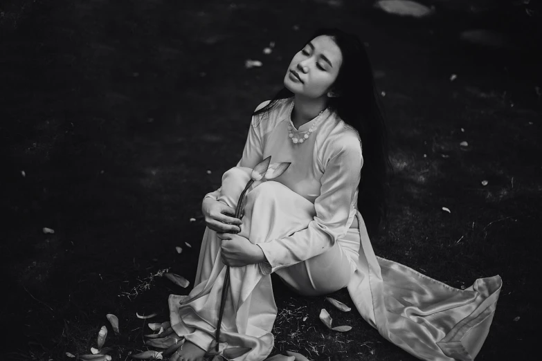 a black and white photo of a woman sitting on the ground, by Tan Ting-pho, fine art, ao dai, with closed eyes, white petal, 15081959 21121991 01012000 4k