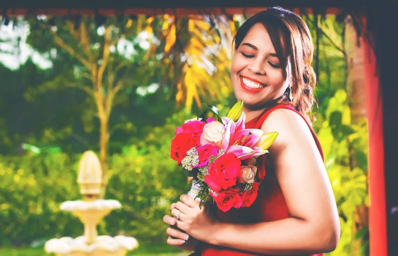 a woman in a red dress holding a bunch of flowers, a portrait, by reyna rochin, pexels, smiles and colors, post processed denoised, 30-year-old woman from cuba, wedding