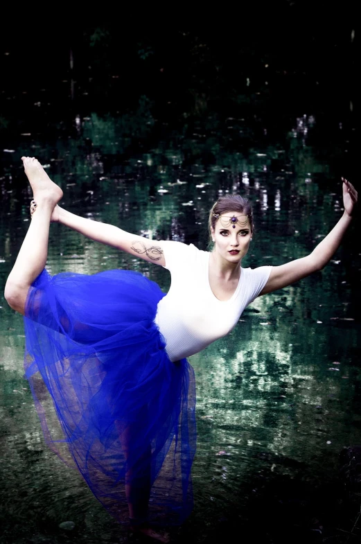 a woman in a blue tutu posing for a picture, arabesque, in a pond, dramatic serious pose, ultramarine, stylized photo