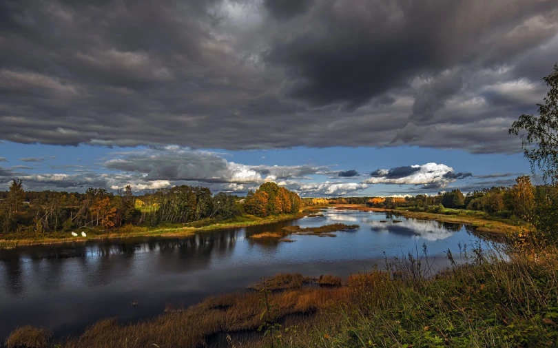 a body of water surrounded by trees under a cloudy sky, a portrait, by Olaf Gulbransson, flickr, hurufiyya, dramatic autumn landscape, winding rivers, floodplains, scotland