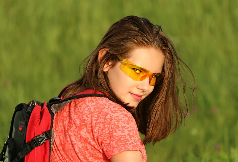 a close up of a person with a backpack, by Erwin Bowien, pixabay, portrait of a young teenage girl, yellow sport glasses, in the steppe, glowing red