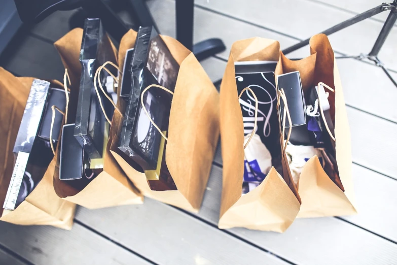 a couple of bags sitting on top of a wooden floor, pexels, people shopping, black and brown colors, many copies of them, packaging