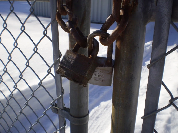 a padlock attached to a chain link fence, by Tom Carapic, flickr, winter, metal key for the doors, burn, [ realistic photo ]!!