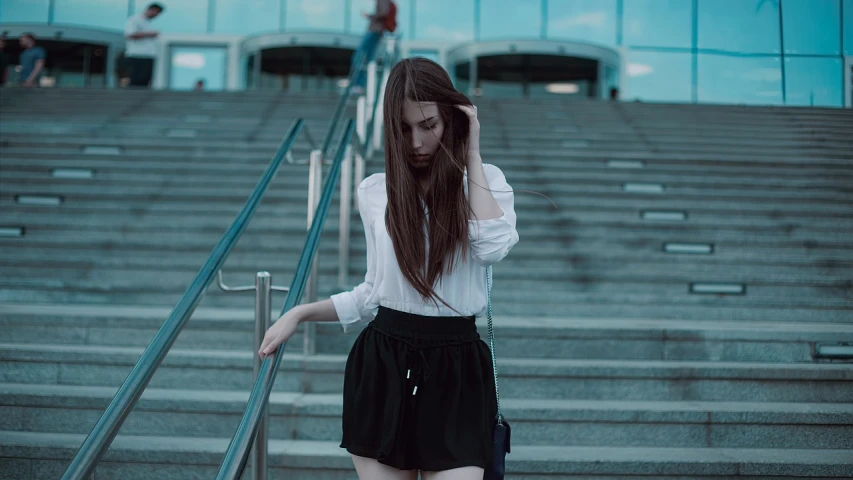 a woman walking down a flight of stairs, a picture, inspired by Elsa Bleda, tumblr, aestheticism, young woman with long dark hair, wearing black shorts, wearing a white blouse, depressed girl portrait