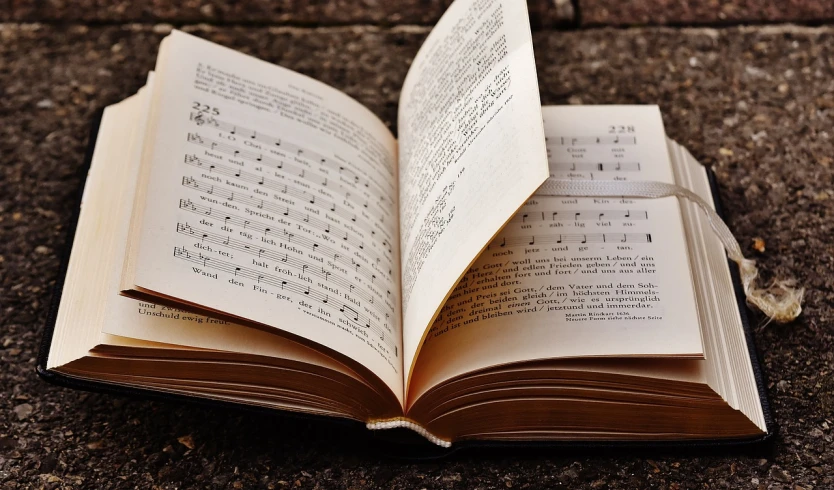 an open book sitting on top of a sidewalk, a photo, by Kurt Roesch, pixabay, musical notes, sing with me, finely textured, face made of notation
