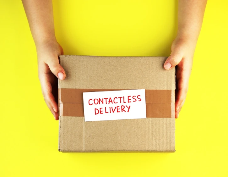 a person holding a cardboard box with contactless delivery written on it, a stock photo, by Thomas Dalziel, shutterstock, conceptual art, contracept, on yellow paper, case, close-up photo