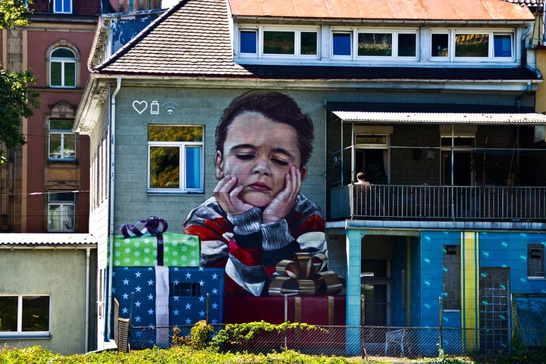 a large painting on the side of a building, inspired by Maler Müller, cute boy, photobashing, stacked houses, sad look