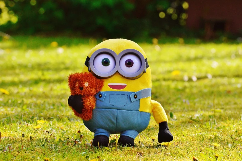 a minion holding a teddy bear in the grass, stuffed toy, 2019 trending photo, 🦩🪐🐞👩🏻🦳, children's toy