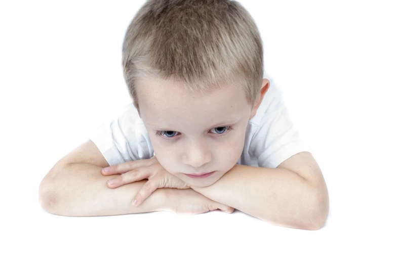 a young boy is posing for a picture, downward somber expression, face centred, background is white, sensory processing overload