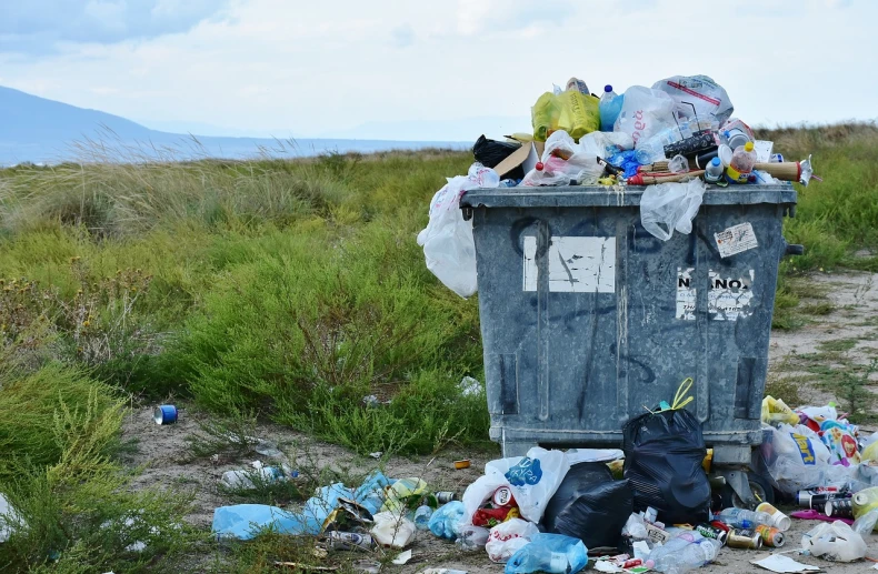 a trash can sitting in the middle of a field, a picture, shutterstock, plasticien, crates and parts on the ground, hill, shore, drag