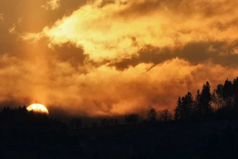 the sun is setting behind the clouds in the sky, by Zoran Mušič, flickr, romanticism, orange mist, hillside, covered in clouds, vibrant but dreary gold