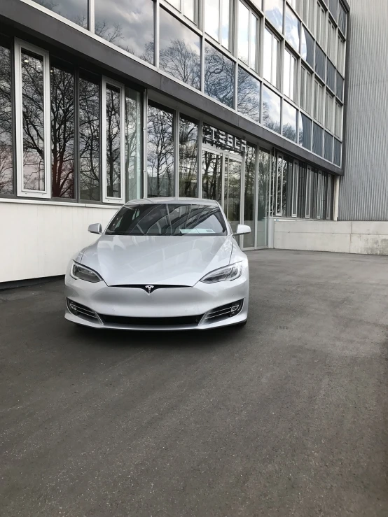 a silver car parked in front of a building, by Kurt Roesch, unsplash, elon musk, with a white muzzle, smooth white surroundings, photo taken with an iphone