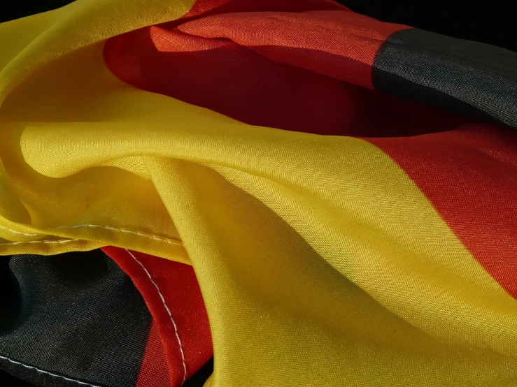 a close up of a red, yellow and black flag, by Dietmar Damerau, chiffon, realistic, seams, germany