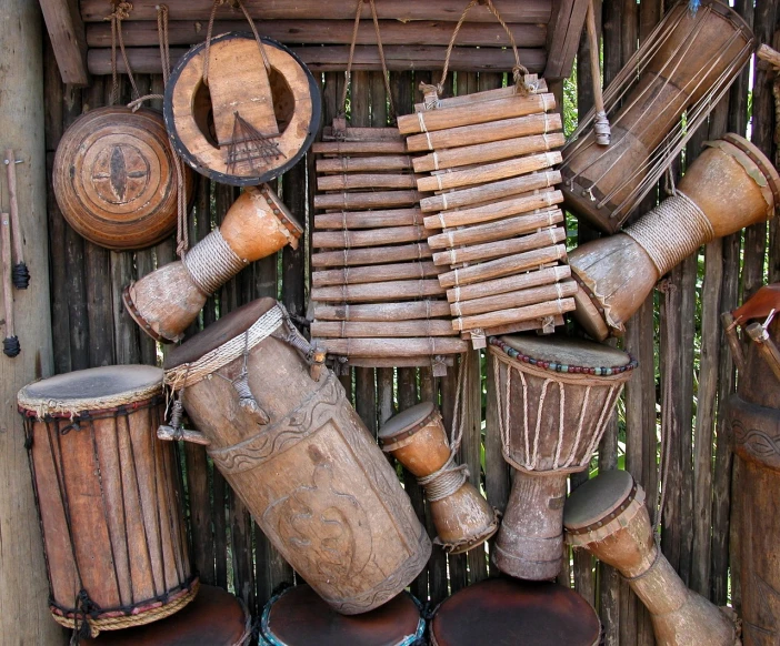 a bunch of drums sitting on top of a wooden fence, a picture, flickr, assemblage, tiki, shaking, ivory, ancient”