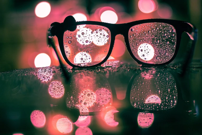 a pair of glasses sitting on top of a table, a picture, by Matthias Weischer, psychedelic droplets of water, pink cloud bokeh, retro effect, late night raining