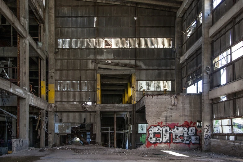 a building that has a bunch of graffiti on it, by Richard Carline, flickr, abandoned steelworks, very sparse detail, cavernous, clean long lines