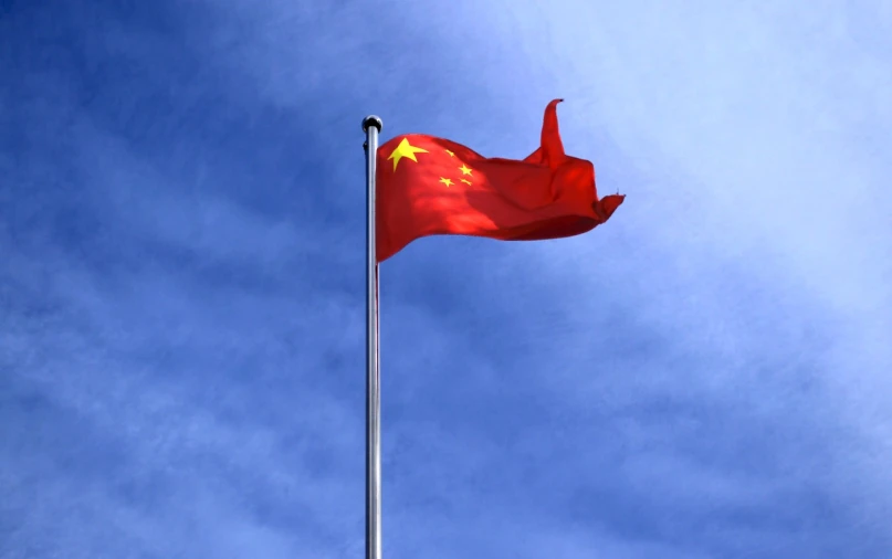 a chinese flag blowing in the wind against a blue sky, by An Zhengwen, istockphoto, three-dimensional, video, high quality]