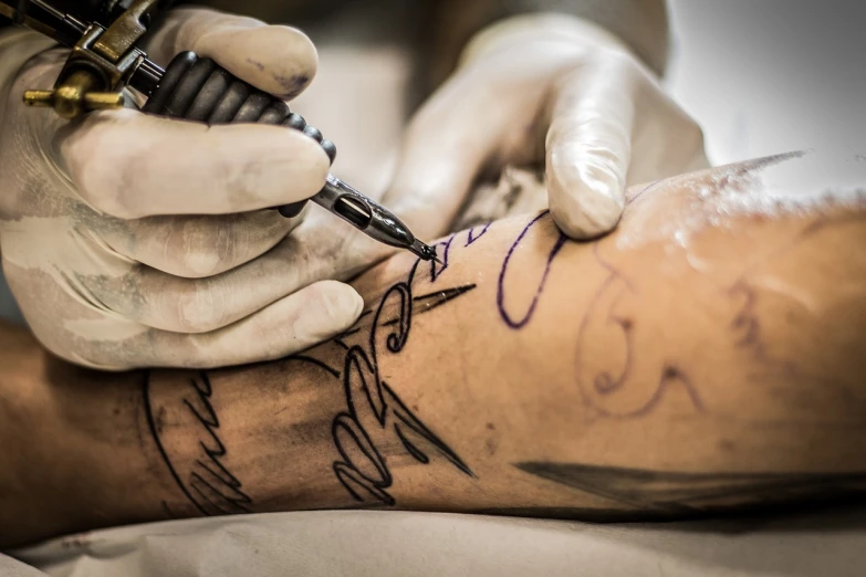 a man getting a tattoo on his leg, a tattoo, by Rodney Joseph Burn, pexels, process art, intricate writing, tattoo sketches, surgery, tattoo sketch of a sea
