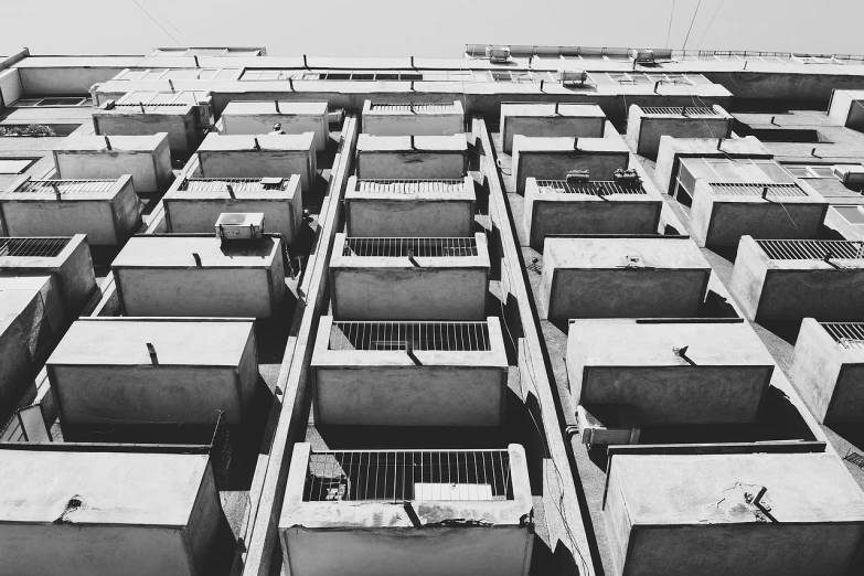 a black and white photo of a tall building, a black and white photo, unsplash, brutalism, crenellated balconies, slums, horizontal view, cages