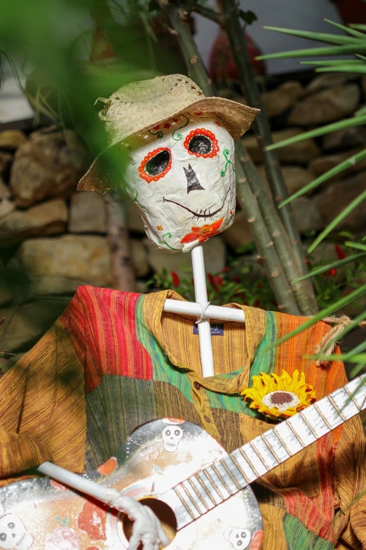 a close up of a figurine of a person with a guitar, folk art, dead plants and flowers, tourist photo, halloween celebration, chest covered with palm leaves