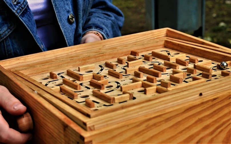 a close up of a person holding a wooden box, by Jon Coffelt, pixabay, mingei, maze, game board, taken in the late 2000s, japanese